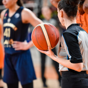 Woman referee keeps the ball during basketball match.