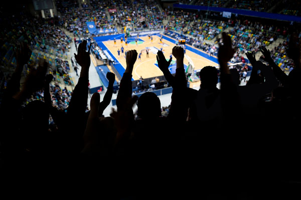 A group of spectator at a professional basketball game cheers at their team